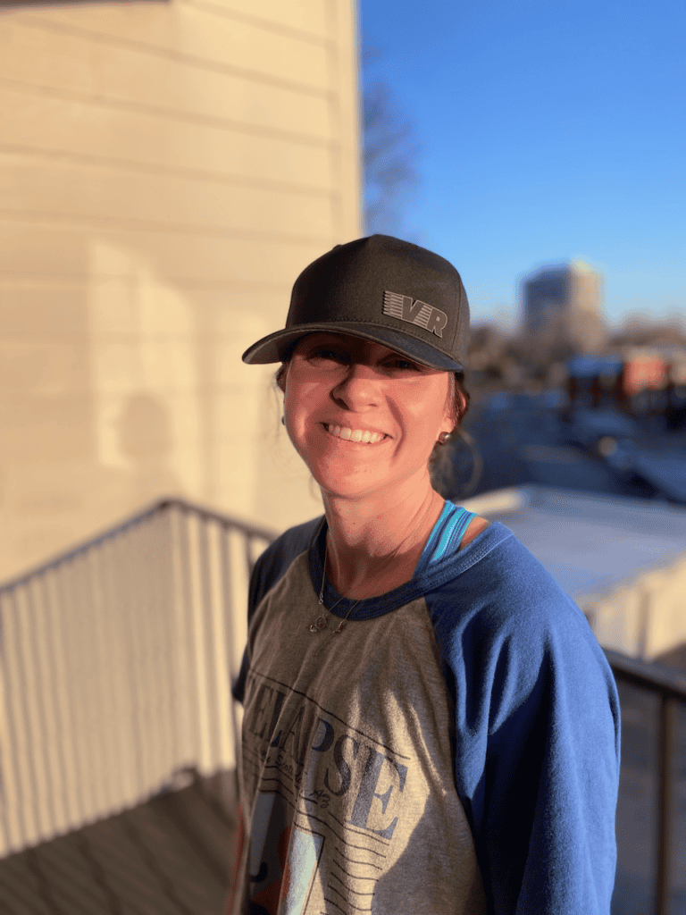 Smiling person wearing a cap on a sunny balcony